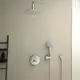 Duschsystem von Ideal Standard mit Kopfbrause und Handbrause, montiert an einer hellen Wand. Zubehör wie Thermostat und Schlauch ebenfalls sichtbar.